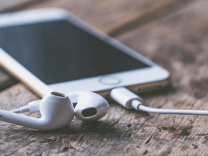 Smartphone with earbuds on a wooden surface.