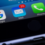 Close-up of a smartphone screen showing app icons with a notification badge indicating 20 unread emails on the Mail app.