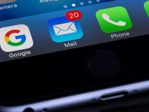 Close-up of a smartphone screen showing app icons with a notification badge indicating 20 unread emails on the Mail app.