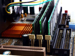 Close-up of a computer motherboard showing RAM slots, PCI expansion slots, and heat sinks.