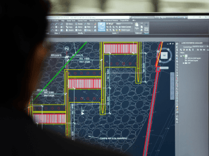 A person viewing a computer monitor displaying detailed architectural design plans or a CAD program.