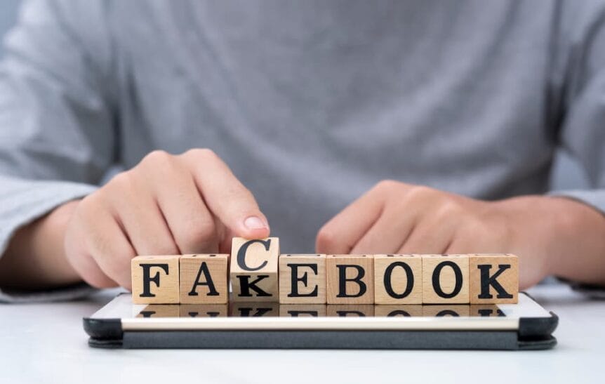 Man flipping scrabble pieces to spell fakebook.