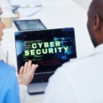 Woman showing a man a laptop that says "Cyber Security" on it.