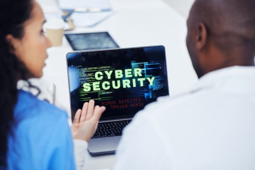 Woman showing a man a laptop that says "Cyber Security" on it.