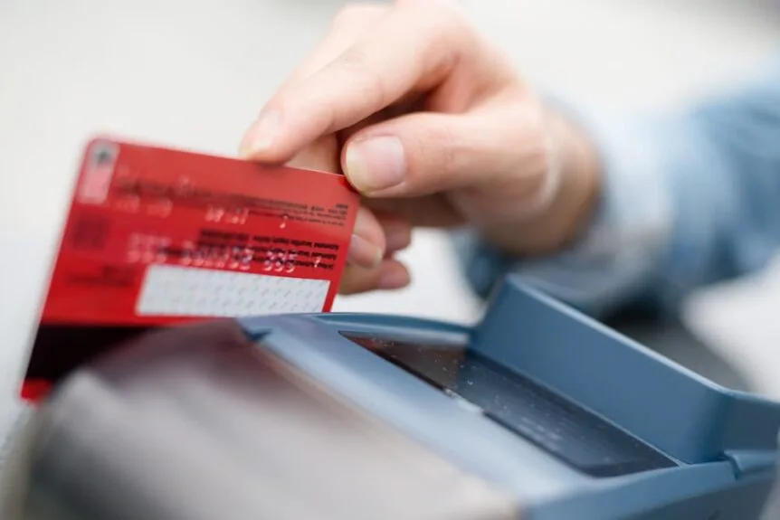 A person swiping a credit card in a terminal.