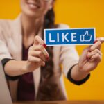 A woman holding a Like sign for social media.