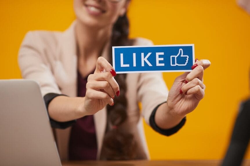 A woman holding a Like sign for social media.