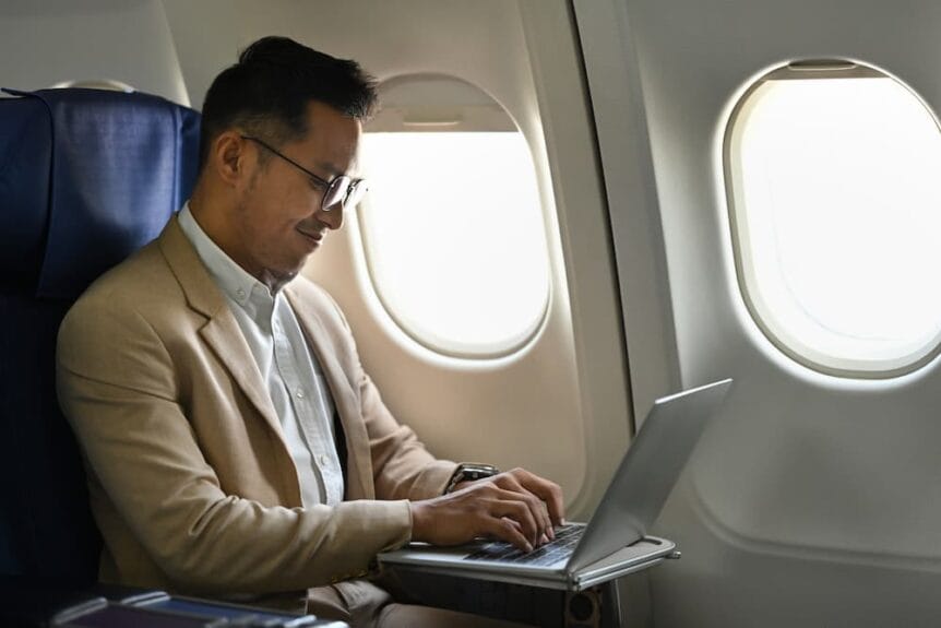 Man flying on a plane using a laptop.